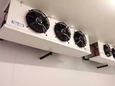 Evaporator coil units with fans mounted high on a walk-in cooler wall