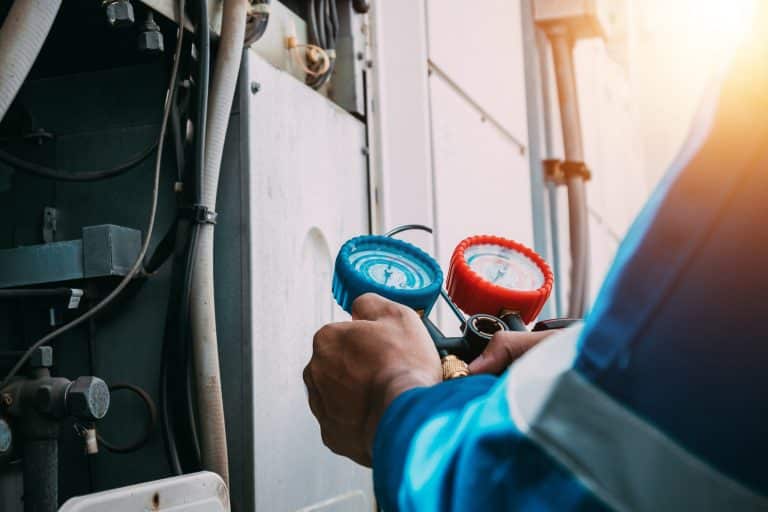 Technician reading refrigerant manifold gauges on a commercial refrigeration system