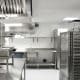 Commercial kitchen with stainless steel reach-in refrigerators, prep tables and an exhaust hood
